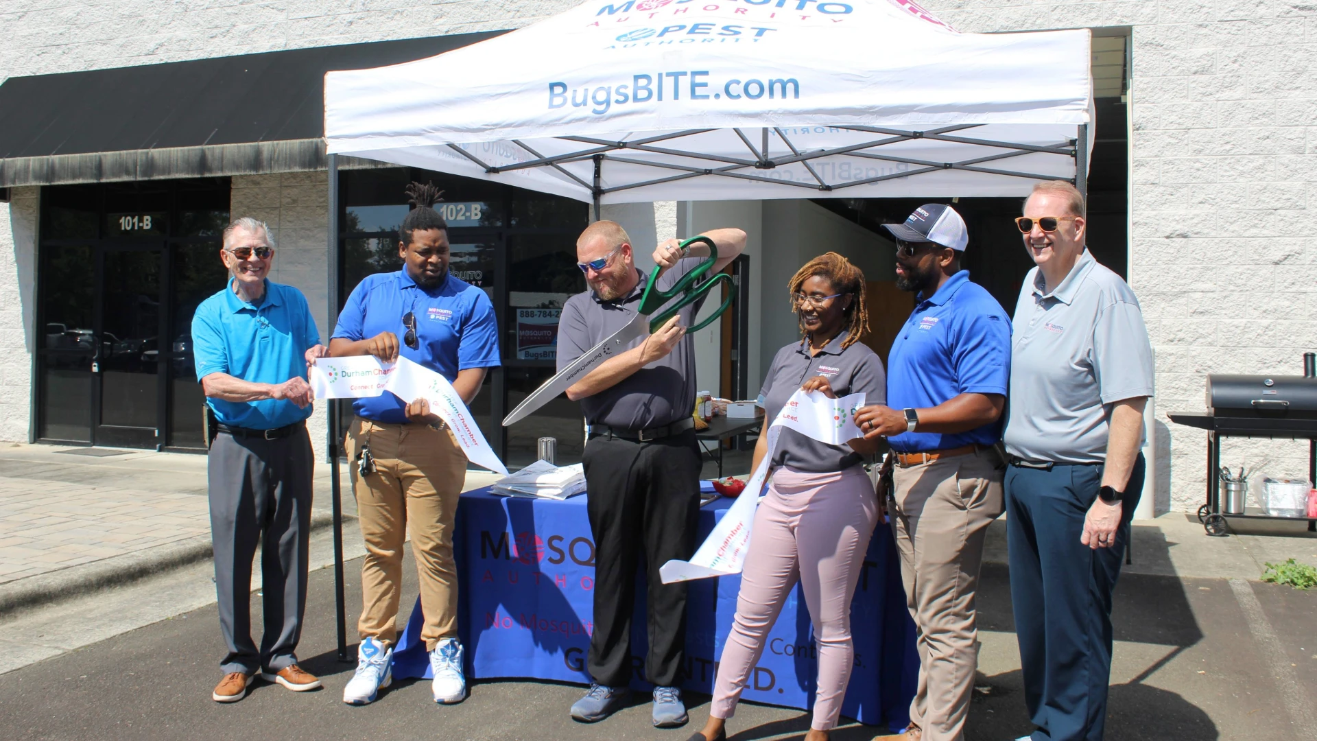 No More Bugs team cutting the ribbon during the grand opening.
